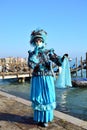 An unidentified man dresses an elaborate azure and black fancy dresses near the Venetian lagoon during Venice Carnival
